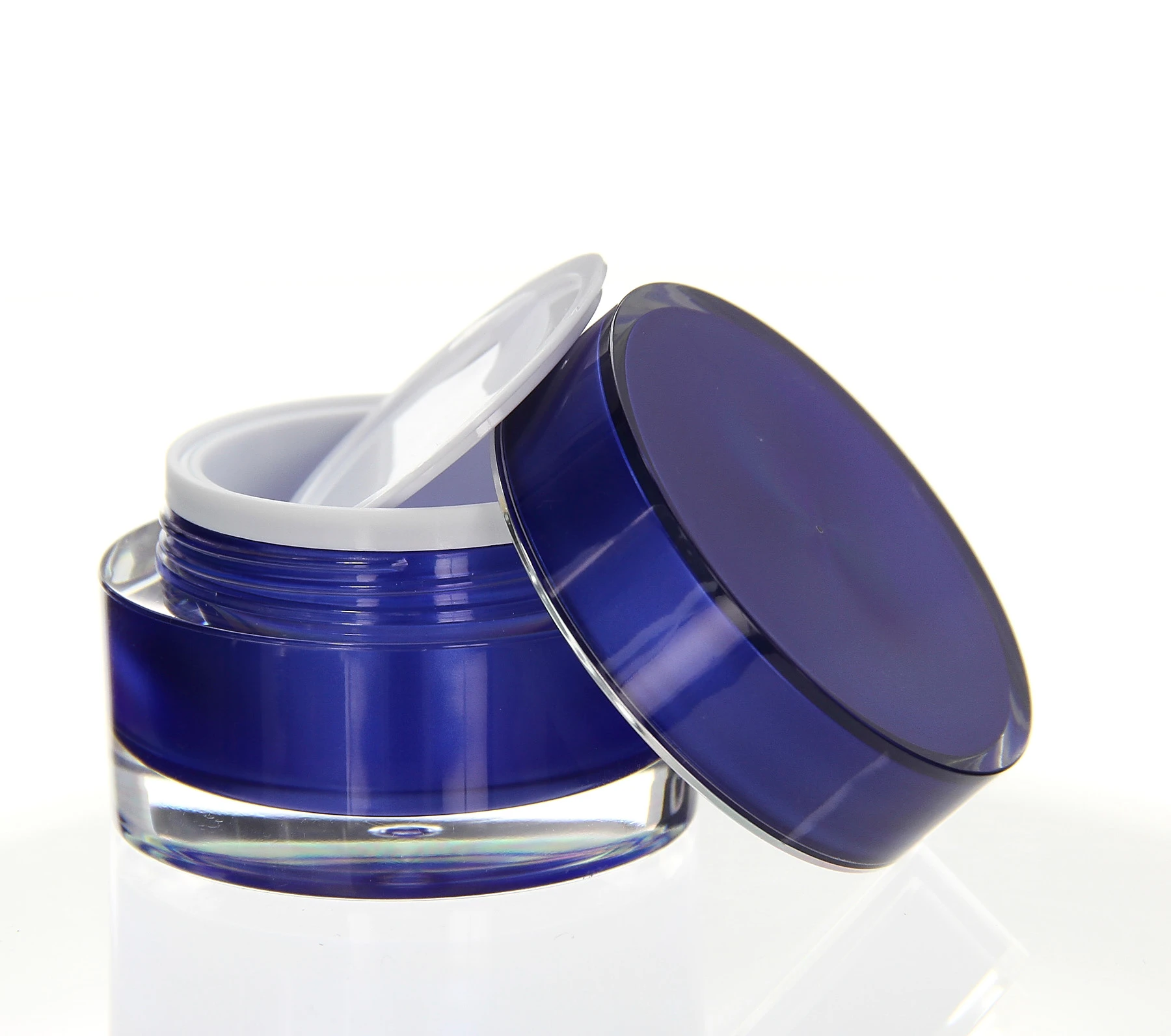 Open 30ml blue acrylic cosmetic jar with white inner lid on light surface