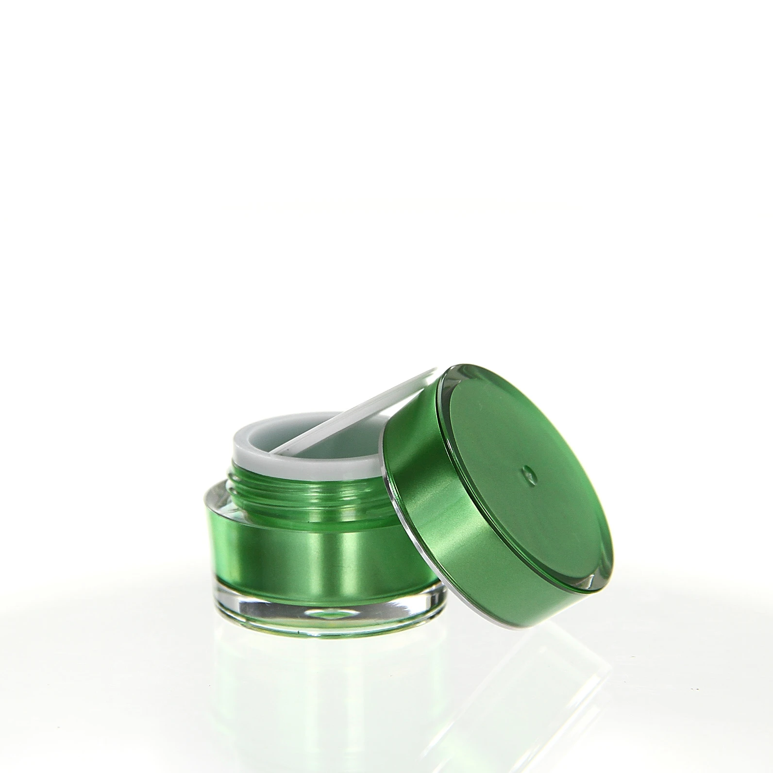 Open 5ml acrylic jar in glossy green with white sealing disc on light pedestal