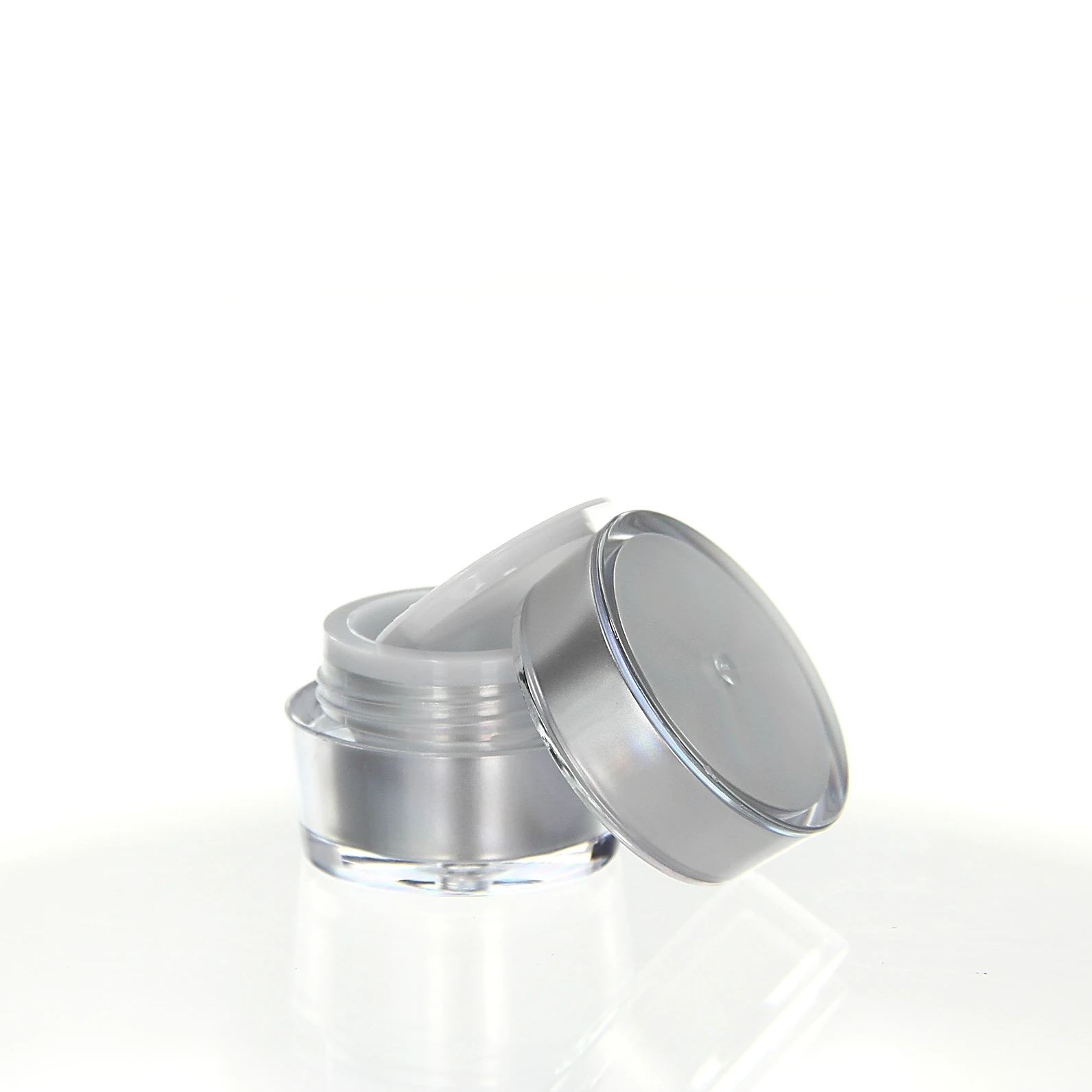 Opened 5ml acrylic jar in shiny silver with white sealing insert on white background