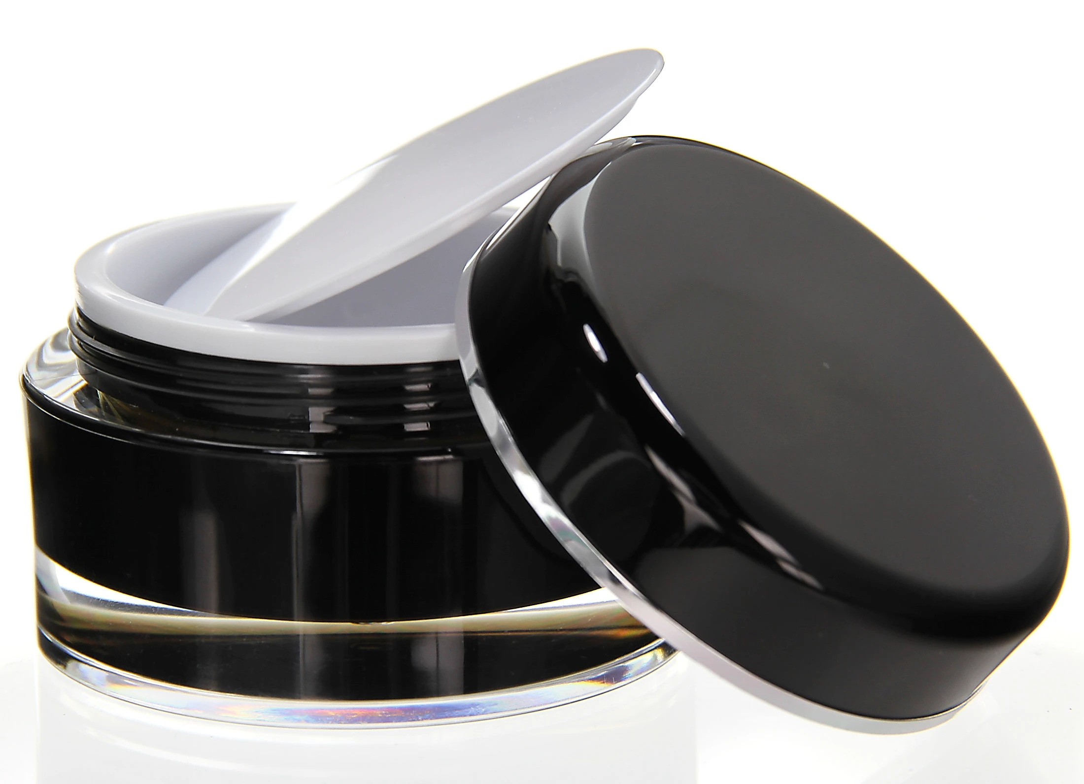 Open 100ml acrylic jar in glossy black with white inner lid and tilted cap on light background
