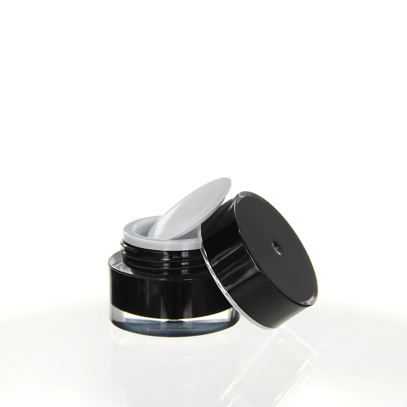 Open 5ml acrylic jar in glossy black with white sealing insert on light pedestal