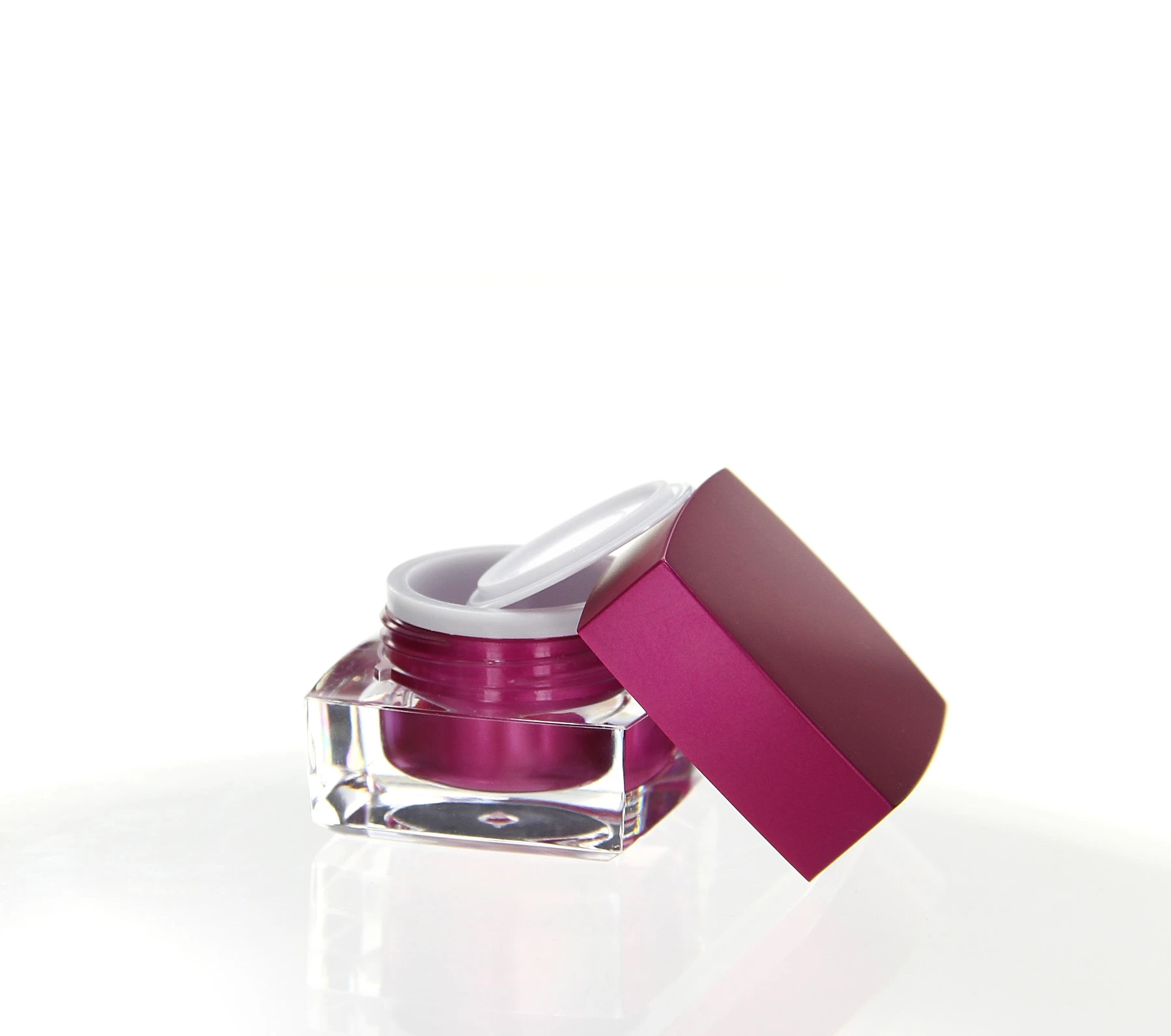 Opened 5ml cosmetic jar in pink with clear acrylic base and white inner lid on white background