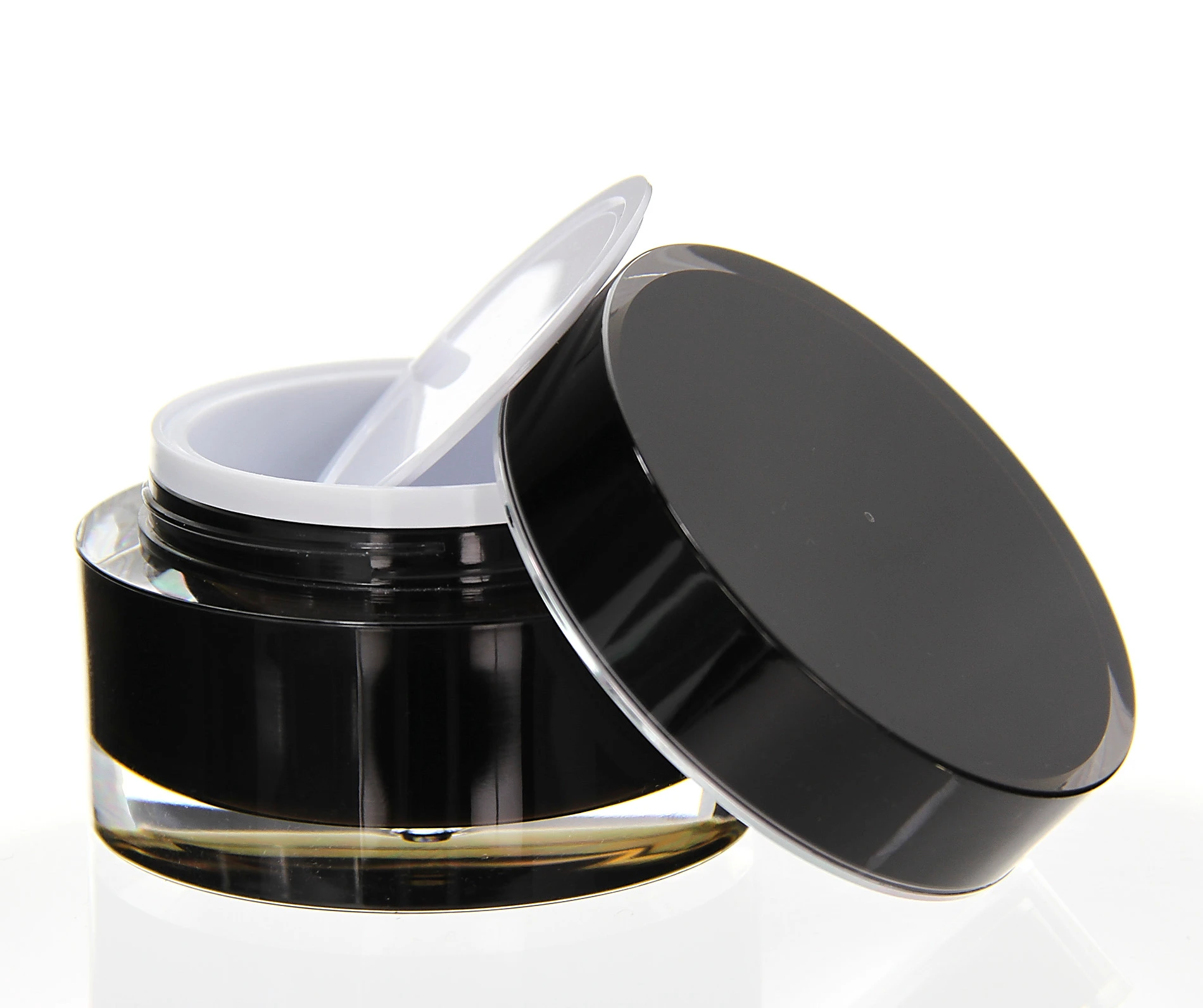 Open 50ml black acrylic jar with white inner lid on light surface